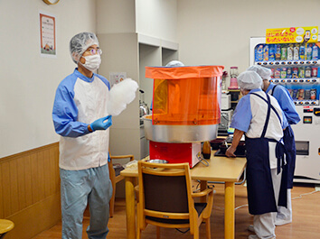 夏祭りで綿菓子を作る職員